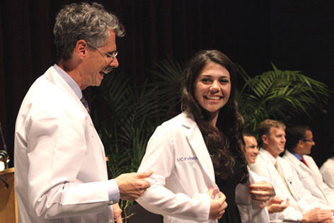 UC Irvine Vice Chancellor Howard Federoff congratulates a new medical student who has just received her white coat at the annual ceremony for incoming students.